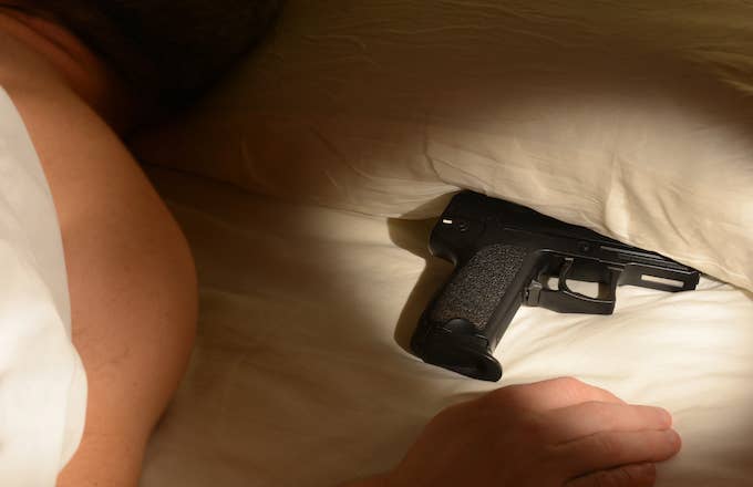 Man in bed with gun underneath pillow.