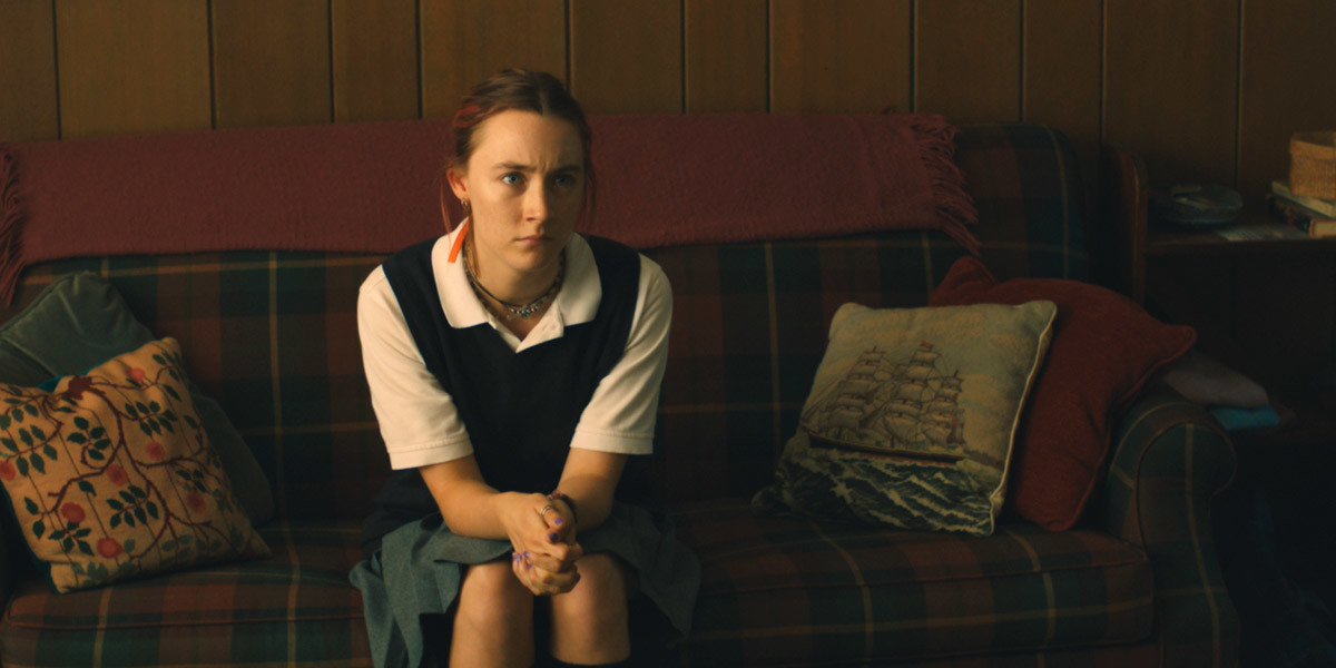 Saoirse Ronan sits on a plaid couch in Lady Bird.