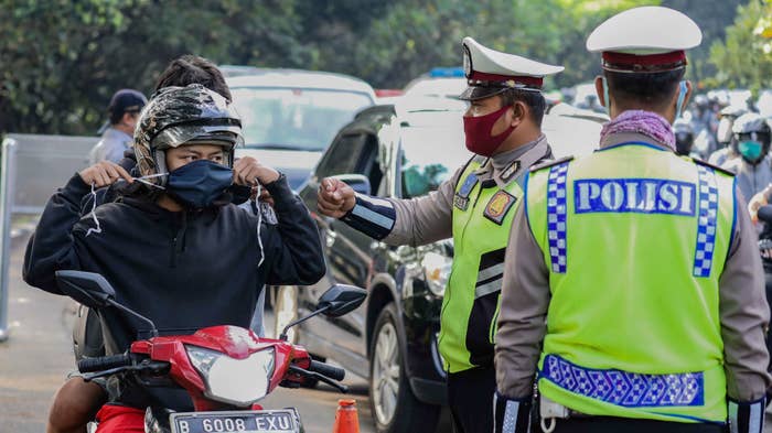 A police officer reminds a motorcyclist to wear his face mask