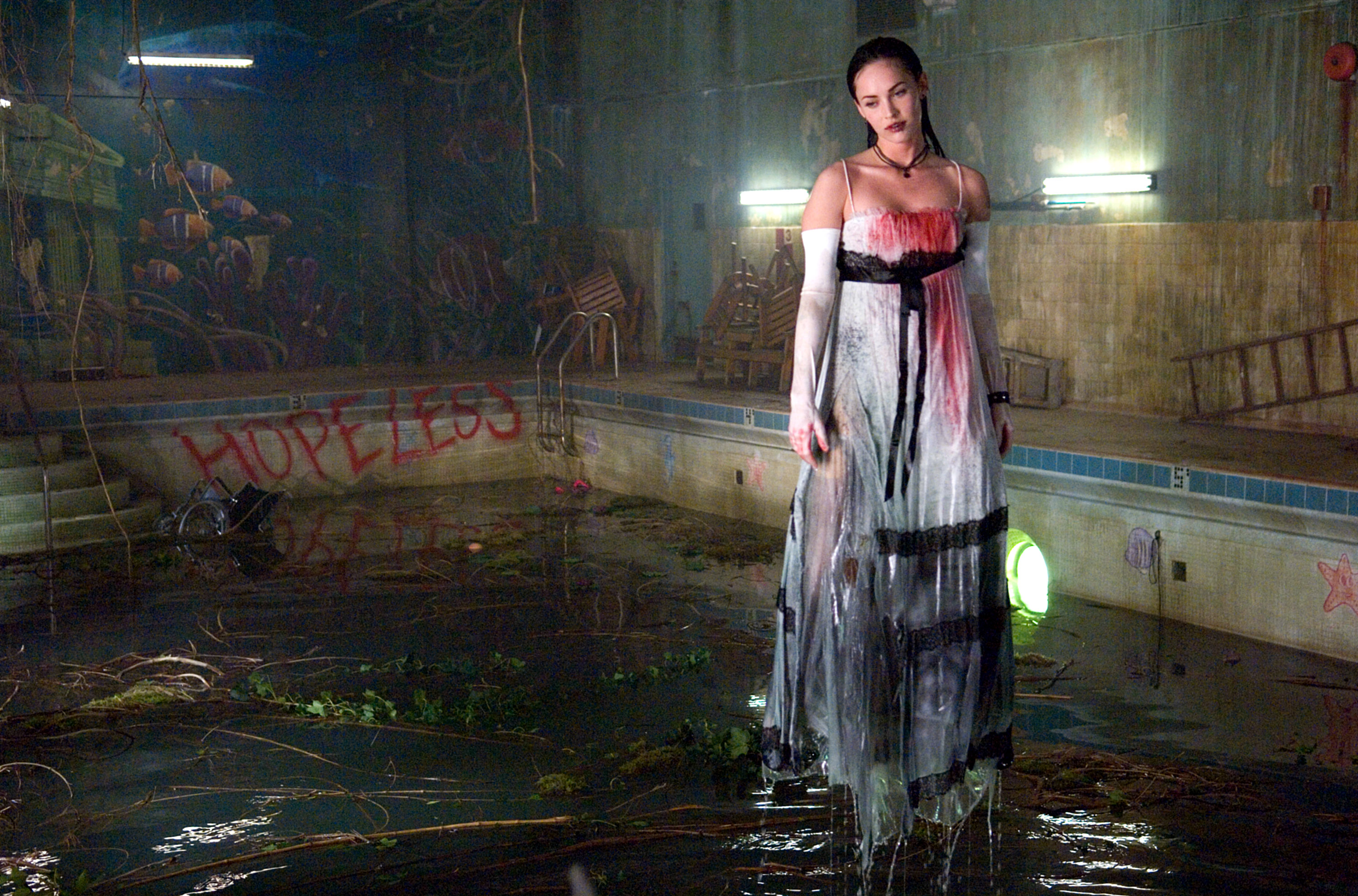 Megan Fox stands in a bloody dress.