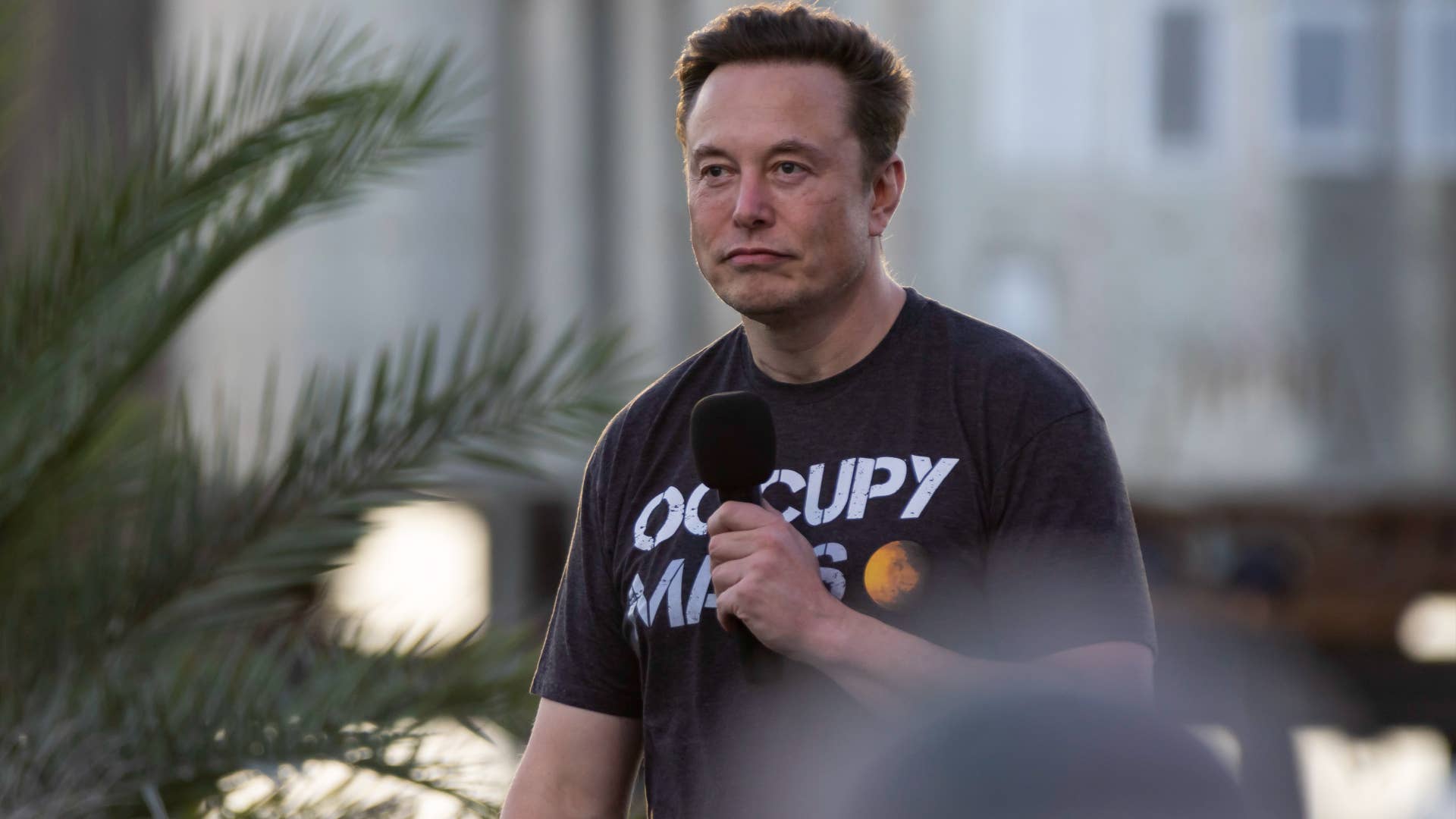 Elon Musk is seen holding a microphone