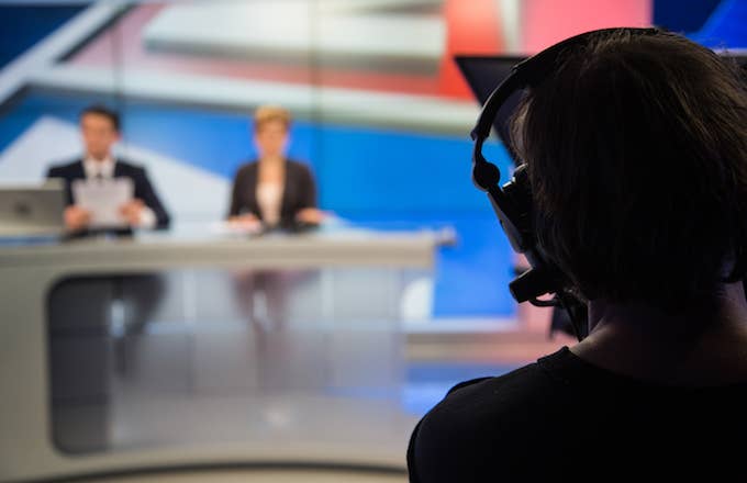 Cameraman filming news in television studio.