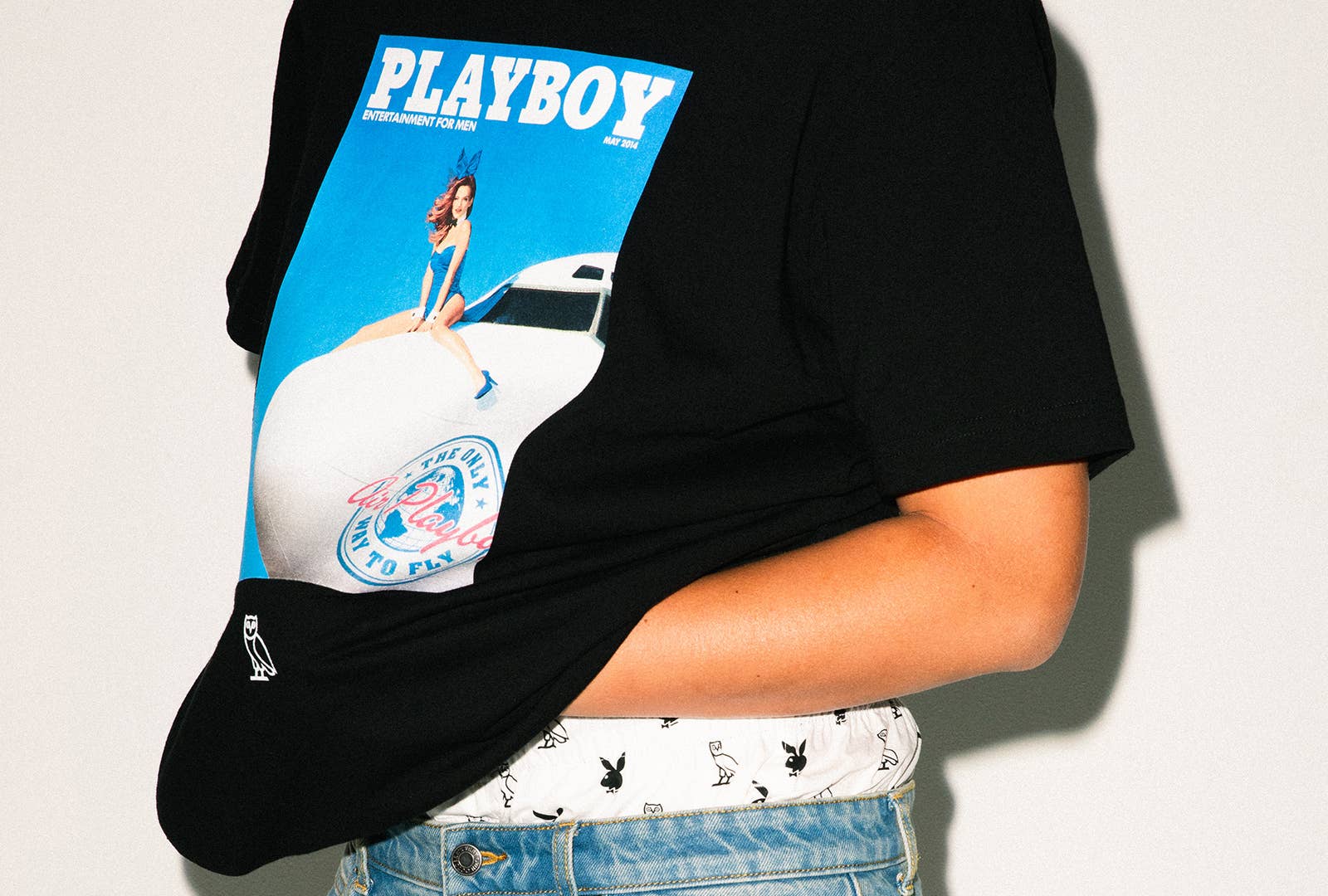 A model wearing black Playboy x OVO shirt with a white pair of boxers and jeans.