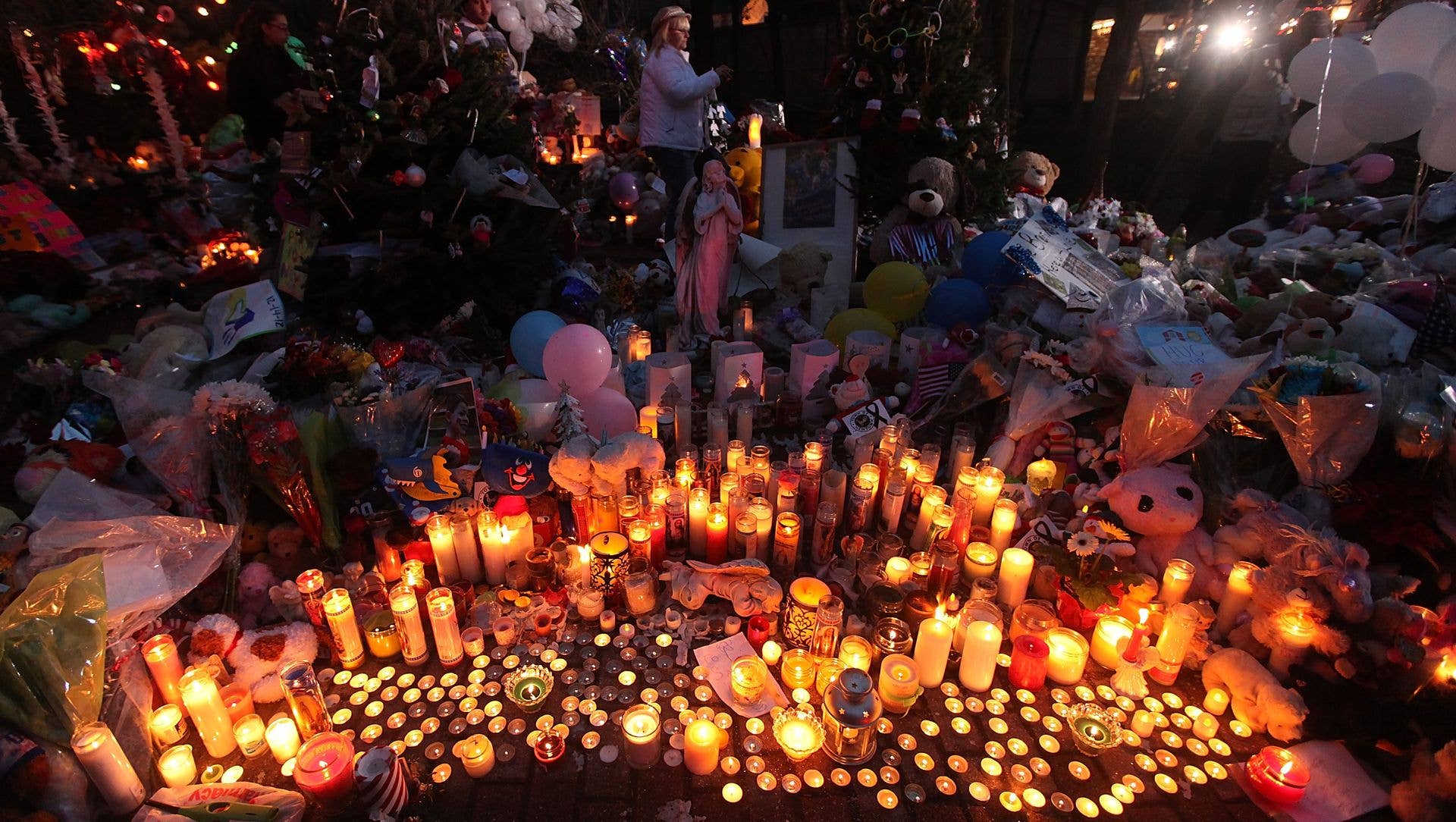 Candles are lit among mementos at a memorial for victims of the mass shooting at Sandy Hook Elementary School