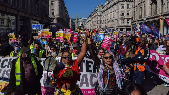 Protesters carrying megaphones hold each other&#x27;s hands during the demonstration in Regent Street