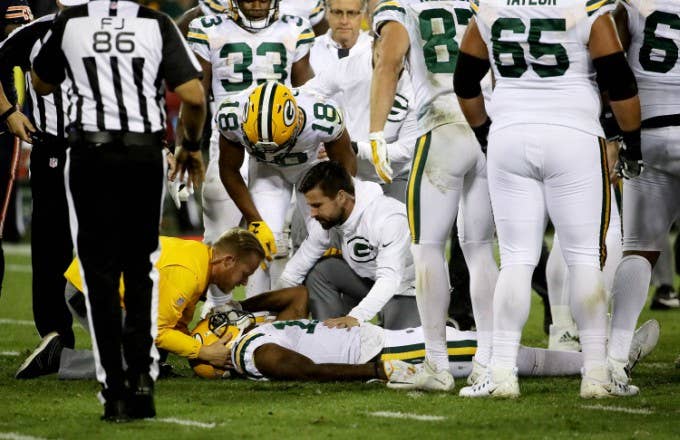 Davante Adams receives medical attention on the field.