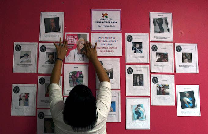 A member of the Pink Unity Collective places a poster on a board, demanding justice.