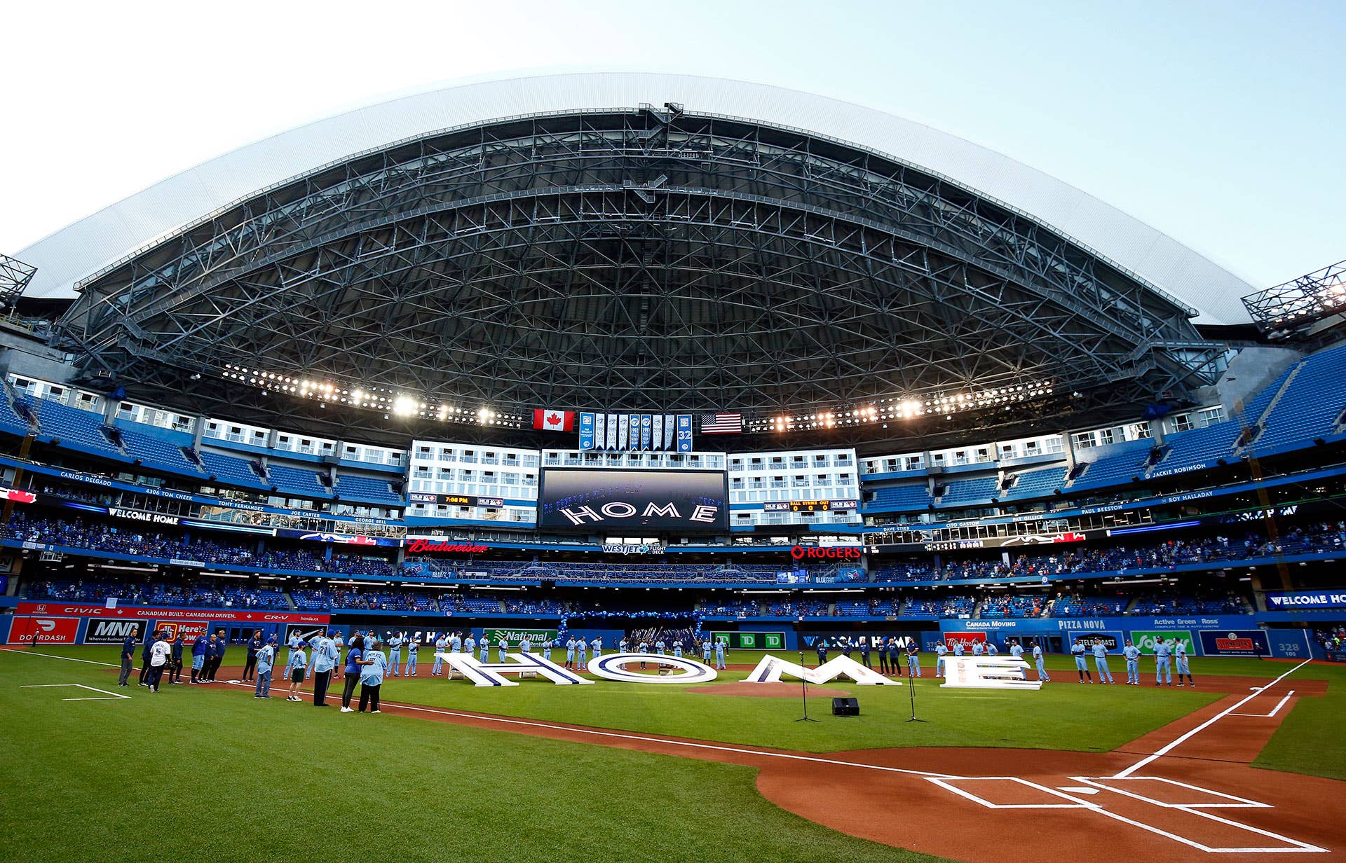 The Toronto Blue Jays line up behind a 'Home' sign to commemorate their first home game in Toronto this season prior to a MLB game against the Kansas City Royals at Rogers Centre on July 30, 2021 in Toronto, Canada.