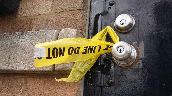 Crime scene tape hangs from a door knob outside of a tow company garage.