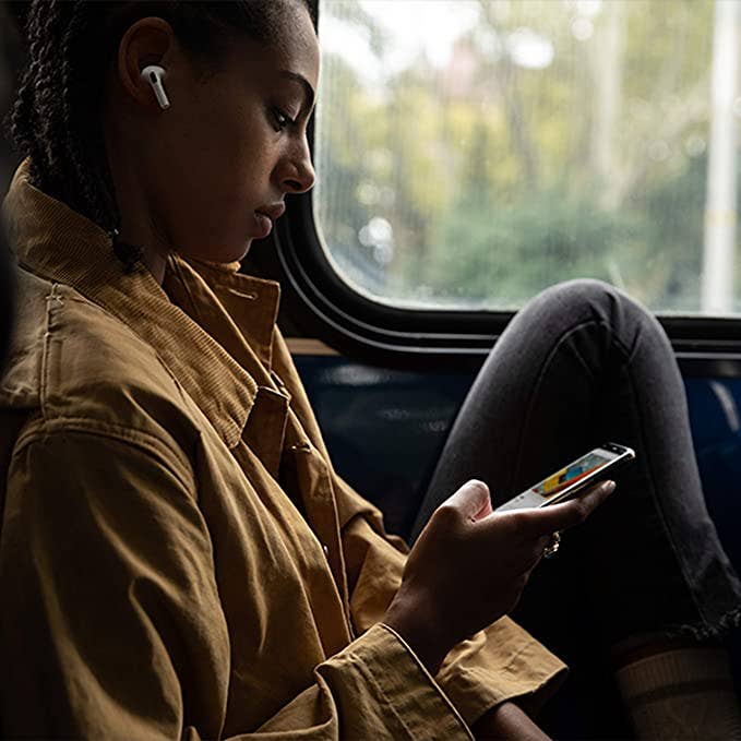 A woman looks at her iPhone while using her Apple AirPods.