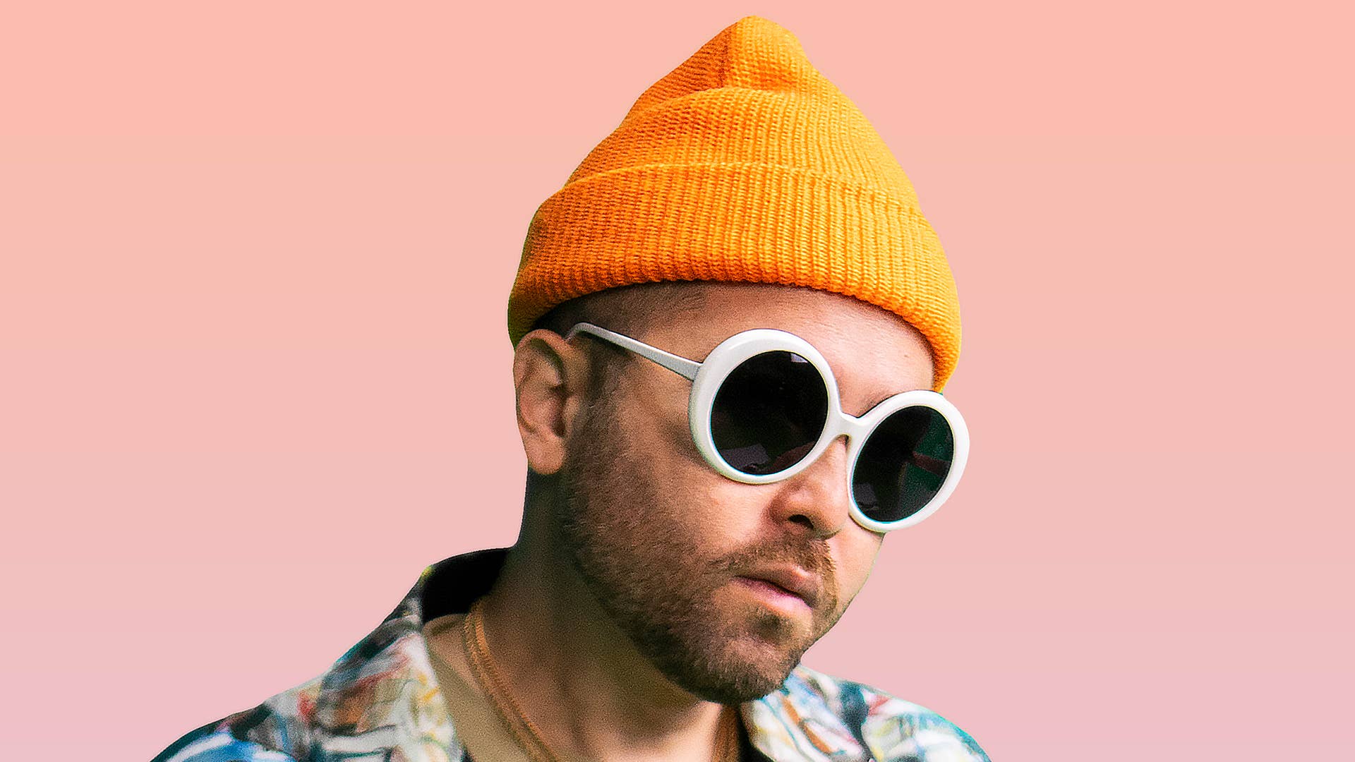 Grandtheft posing in an orange beanie and white shades for his new EP Wild Ways.