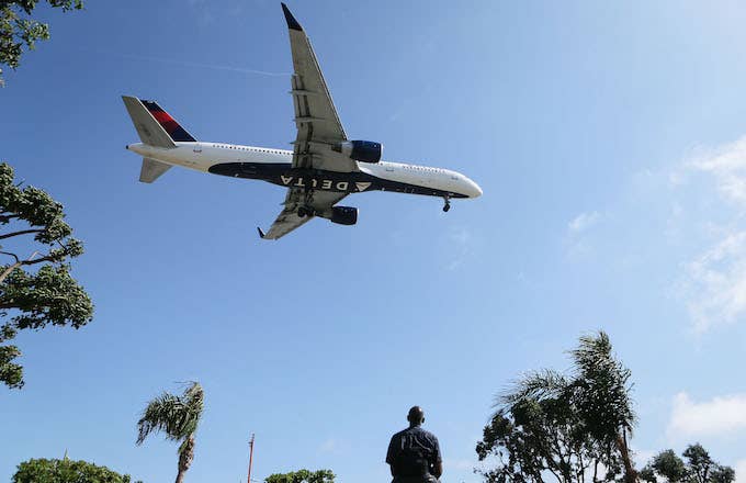 Man watches as a Delta Air Lines plane lands at Los Angeles International Airport.