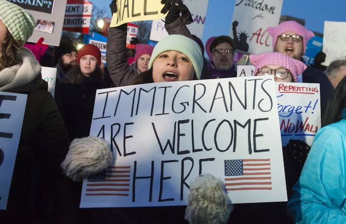 Woman holding &#x27;Immigrants Are Welcome Here&#x27; sign.