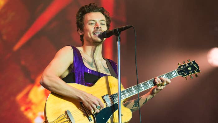 Harry Styles is pictured playing a guitar