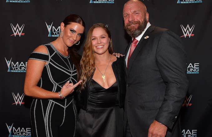 Stephanie McMahon, Ronda Rousey, and Triple H appear on the red carpet.