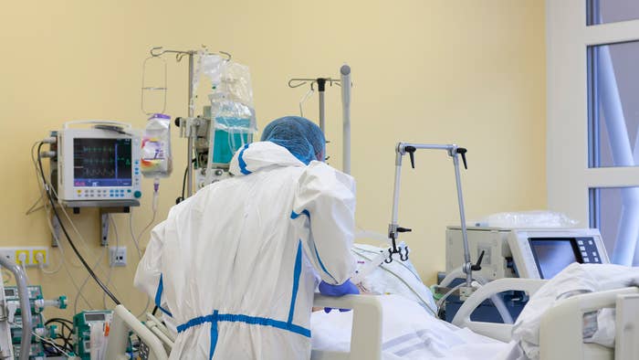 COVID-19 nurse talking to a patient, all-over protective clothing in intensive care unit