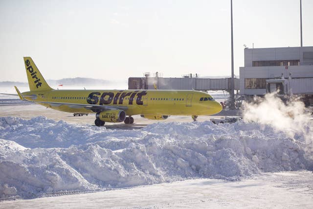 Spirit Airlines airplane prepares to drive around a large snow pile