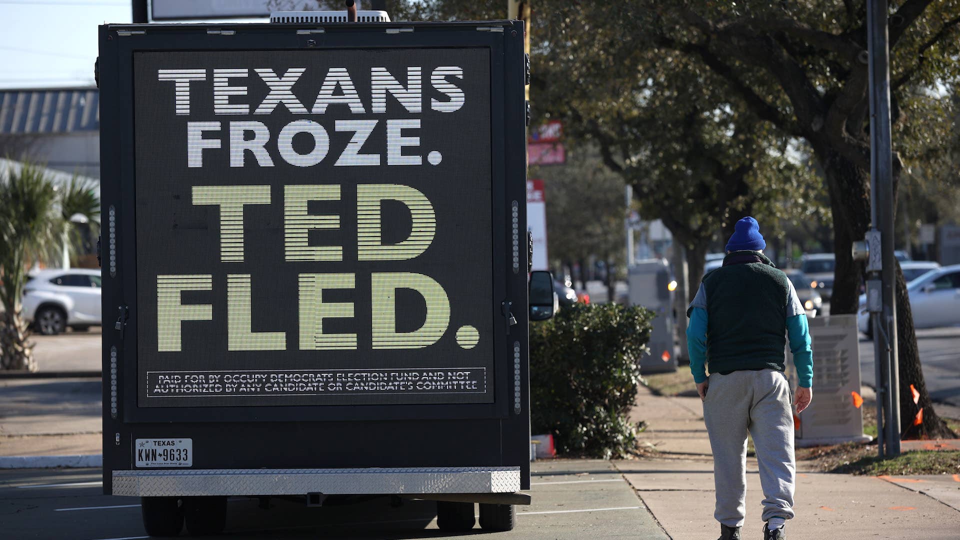 A pedestrian walks by a digital billboard truck with an image of U.S. Sen. Ted Cruz