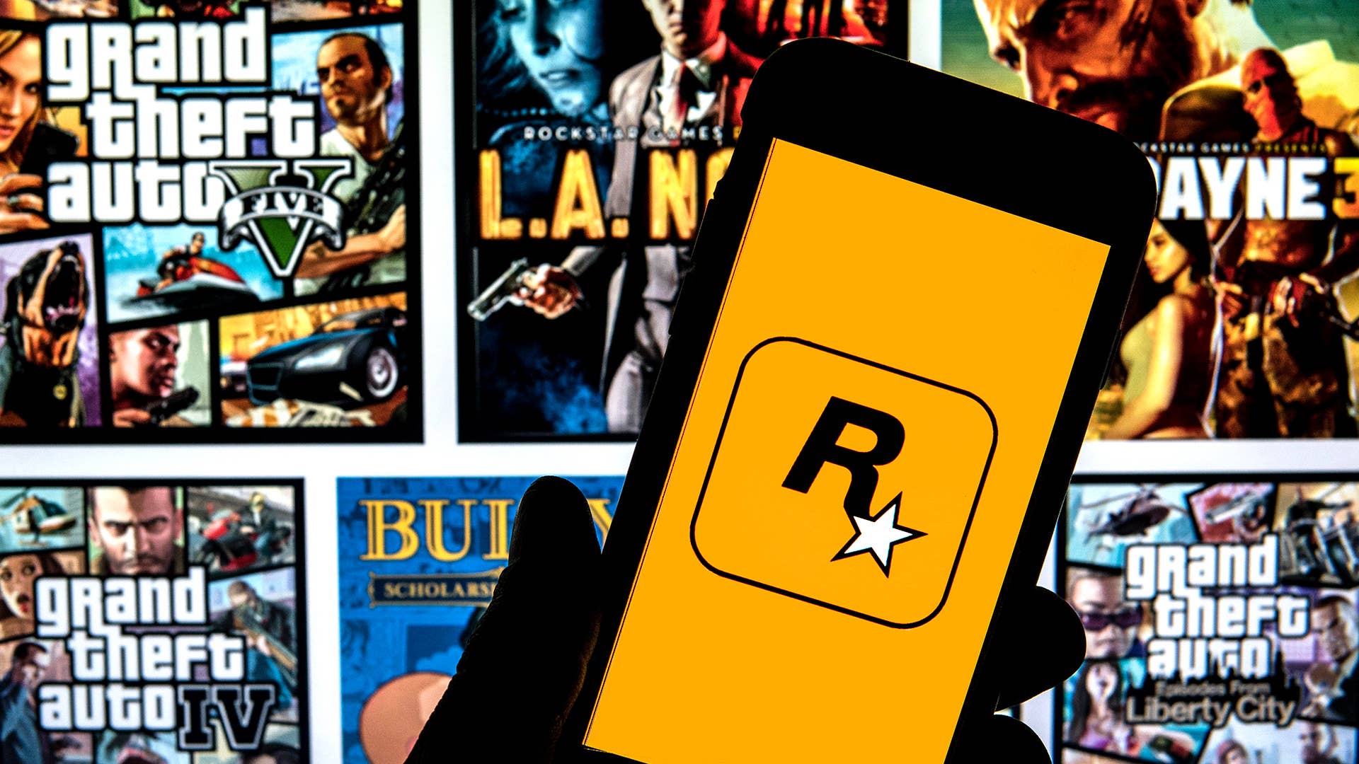 In this photo illustration a Rockstar Games logo seen displayed on a smartphone with video games cover in the background