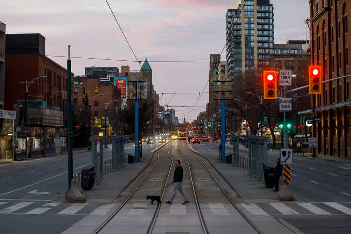 A pedestrian cross the street with a dog as Toronto copes with a shutdown