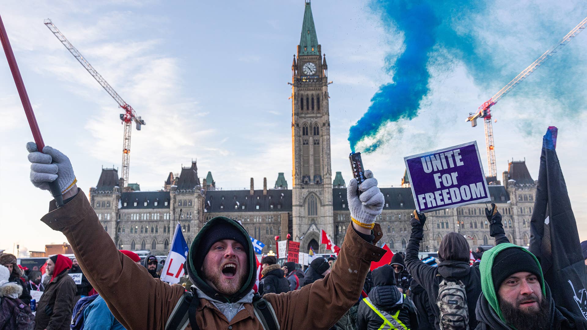 Protestors on parliament hill with signs and smoke flares