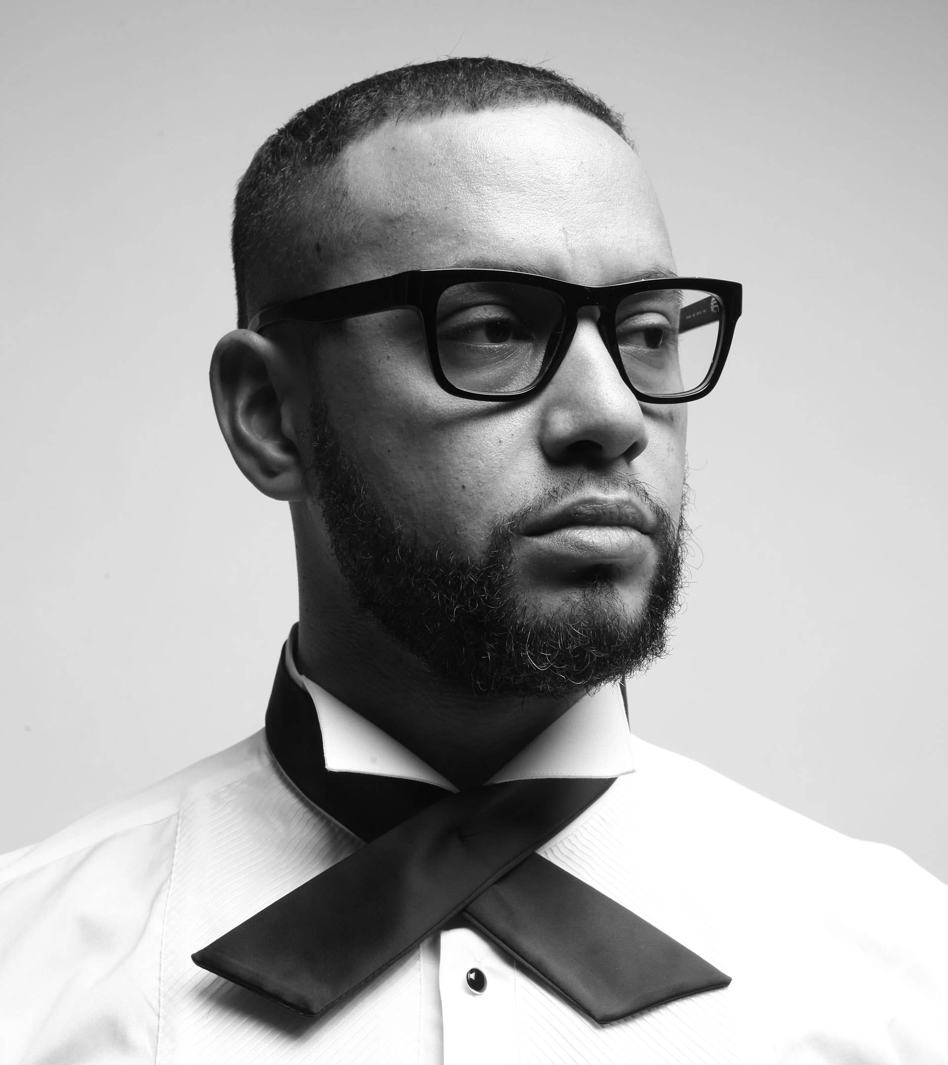 Director X poses in a white shirt and x-shaped tie