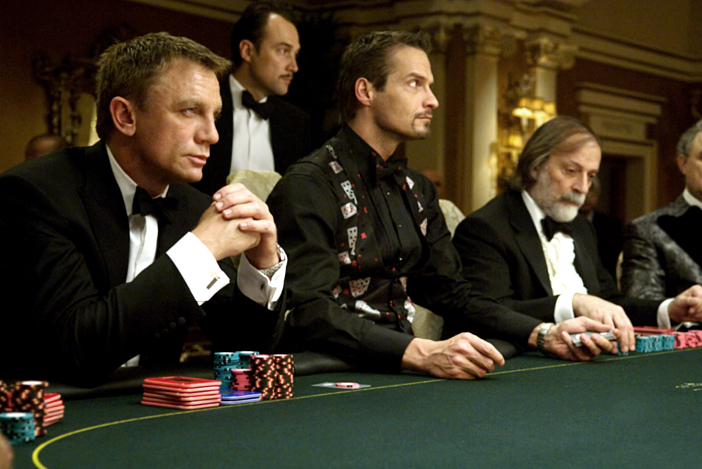 Daniel Craig sits and watches as other players look on.