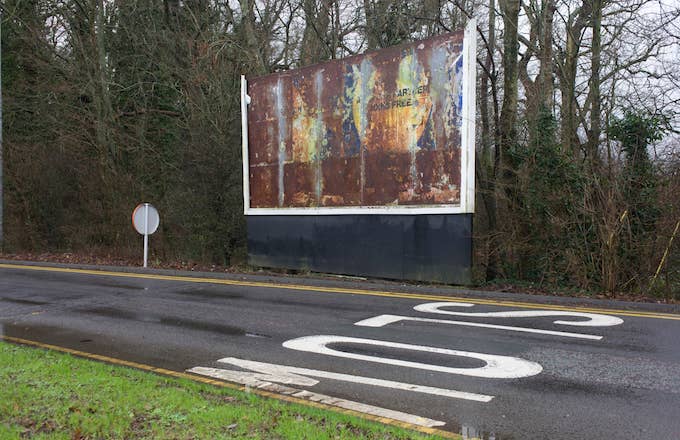 Rusting billboard showing a faded advert landscape at the Reading Services on the M4 motorway