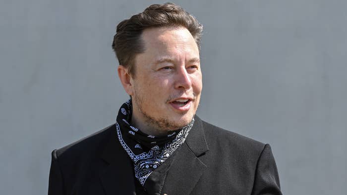 Elon Musk wears a bandana over a blazer.