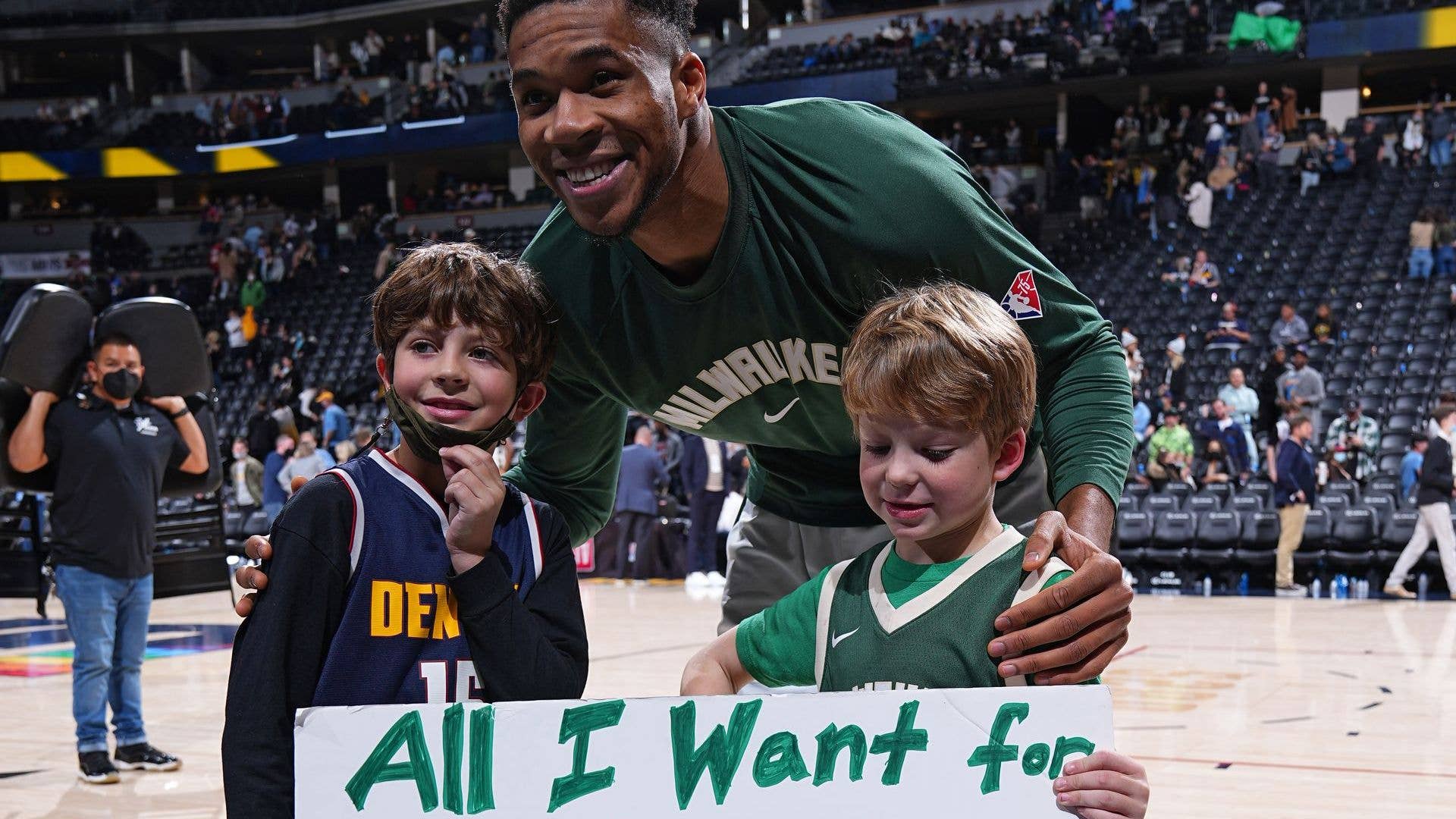 Giannis Antetokounmpo gives his autographed sneakers to a young fan after a game against the Denver Nuggets