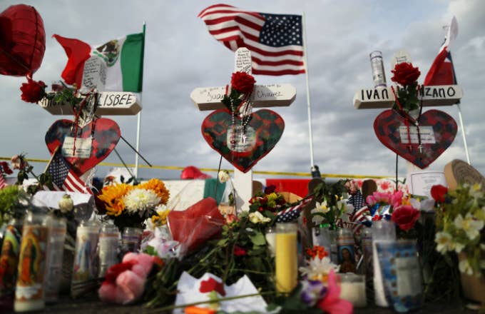 The U.S. and Mexican flags fly above a makeshift memorial for victims