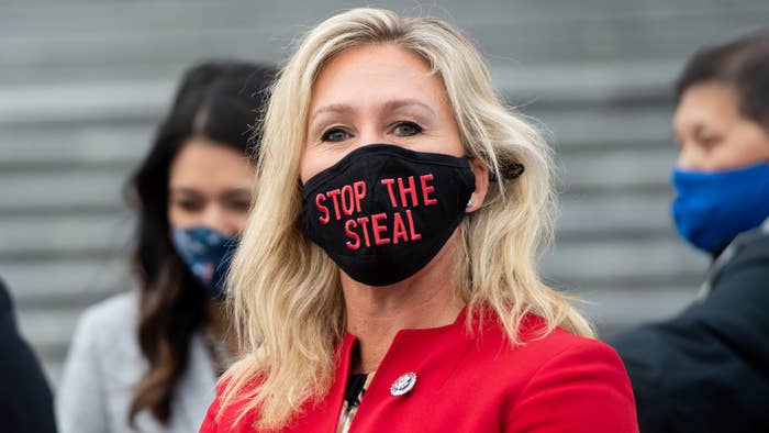 Marjorie Taylor Greene holds up a &quot;Stop the Steal&quot; mask.