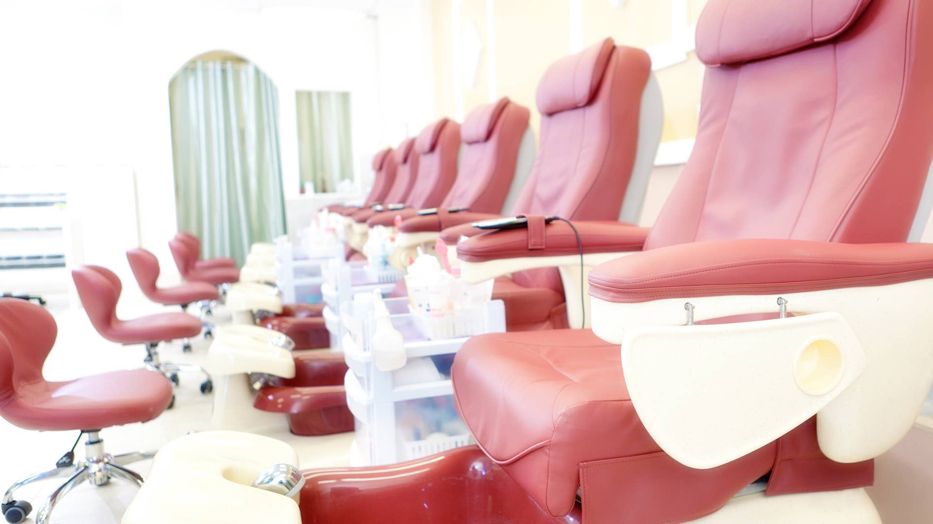 A row of pedicure massage chairs in a row in a clean, bright nail salon small business shop.