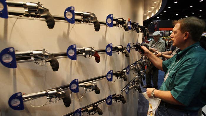 Tim Basington looks over Smith &amp; Wesson pistols at the NRA annual meeting.