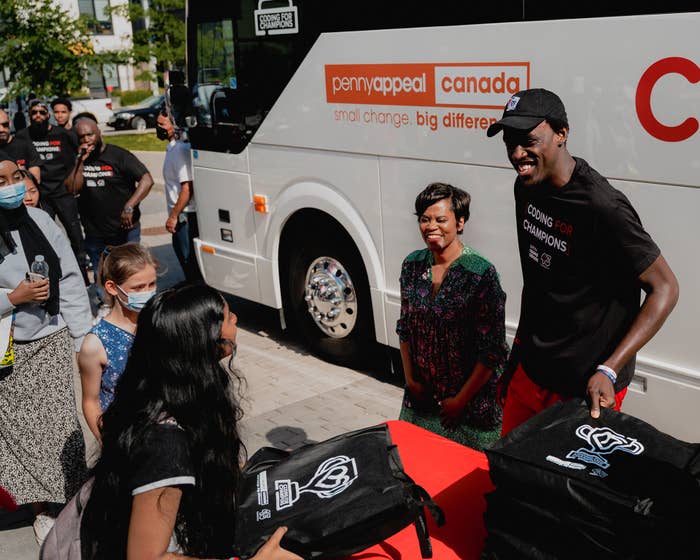 Pascal Siakam and Marci Ien handing out laptops to kids in Regent Park