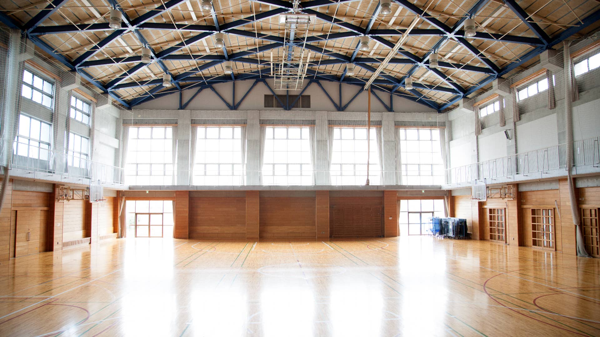 An empty school gymnasium. Basketball court markings.