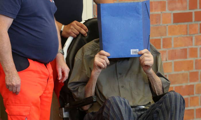 Former Nazi concentration camp guard Josef Schuetz (R) covers his face as he arrives on June 28, 2022 at a gym used as a makeshift courtroom