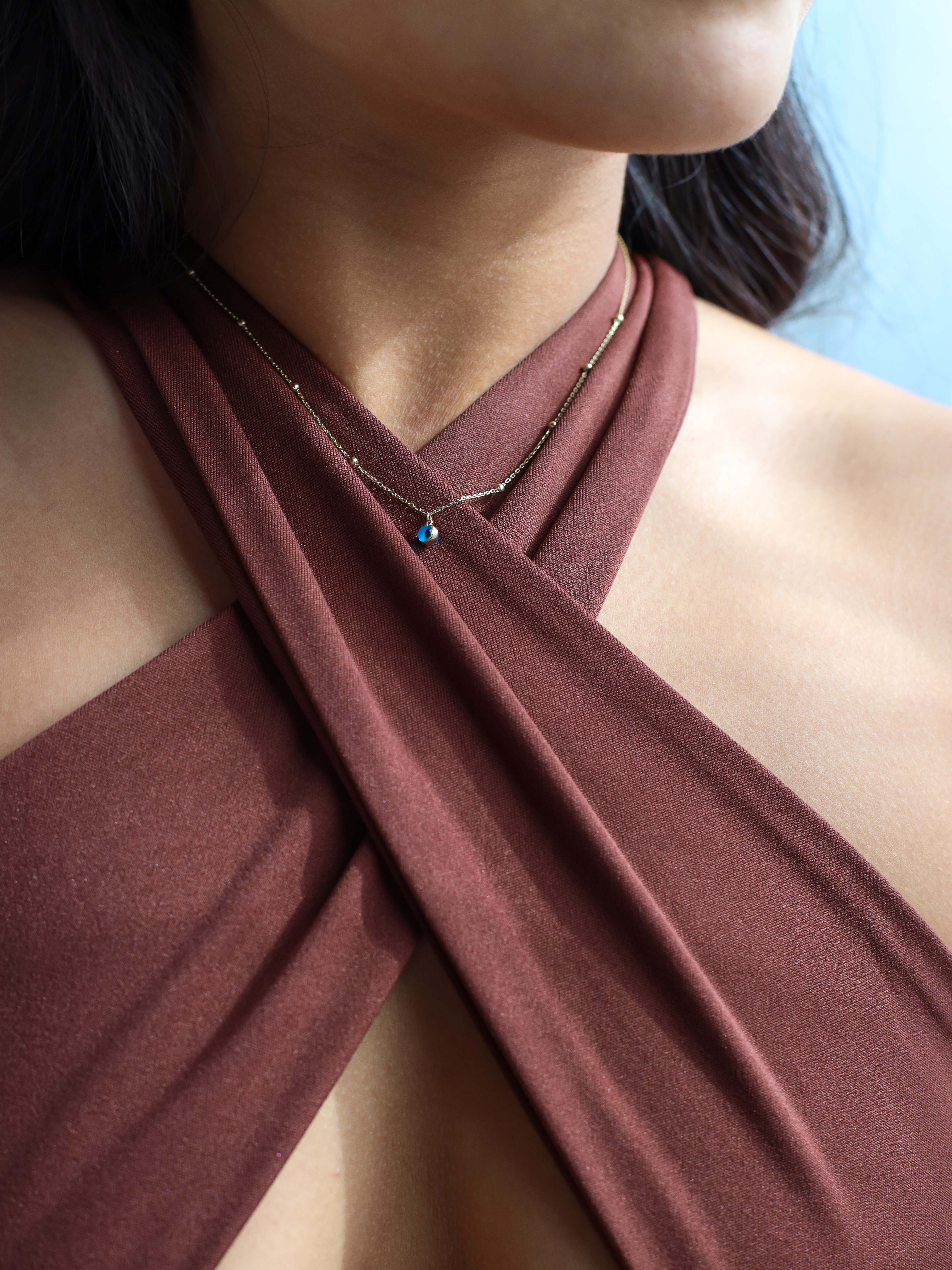 Orijin evil eye necklace around a model&#x27;s neck