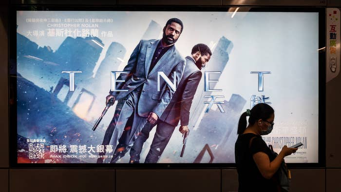 A commuter walks past a poster of Christopher Nolan's blockbuster film Tenet
