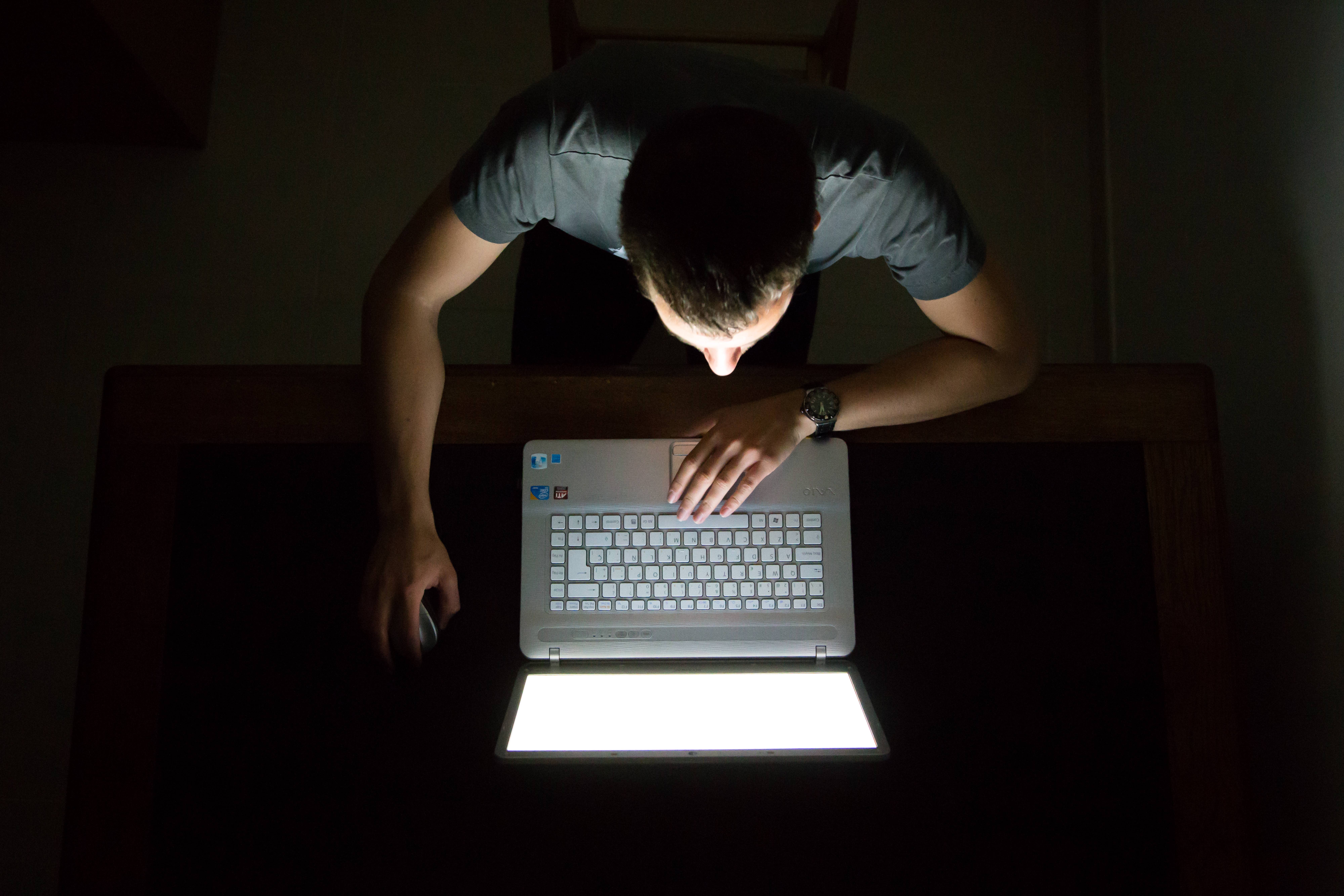 This is a photo of a man on the computer in a dark room.