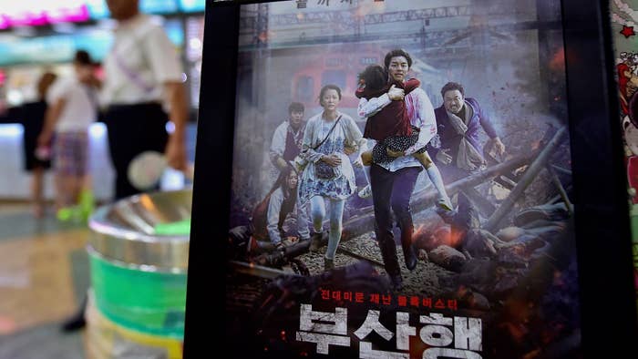 A man walks past a poster of 'Train to Busan'