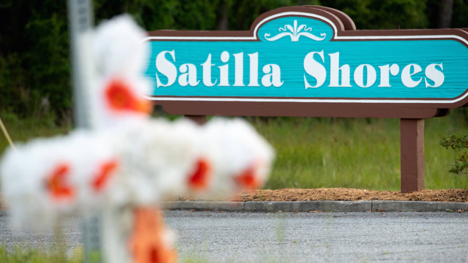 A cross with flowers and a letter "A" sits at the entrance to the Satilla Shores