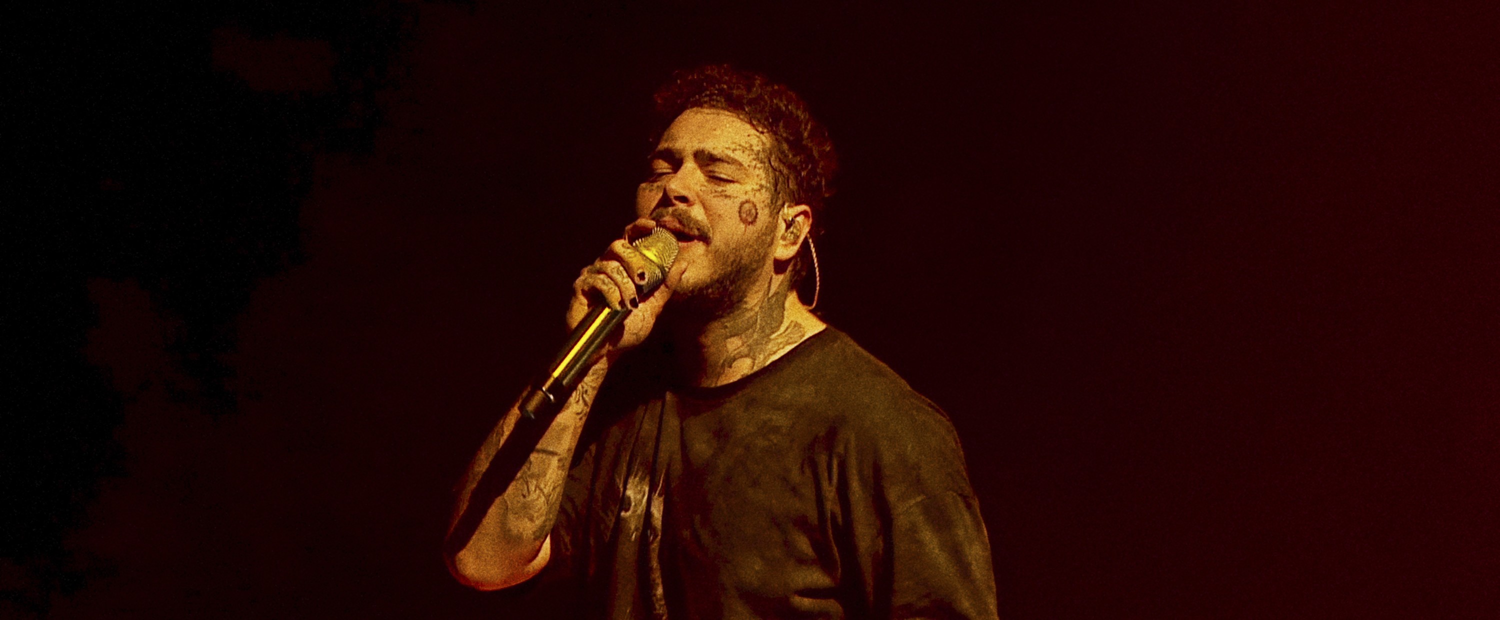 Post Malone with a mic in his hand.