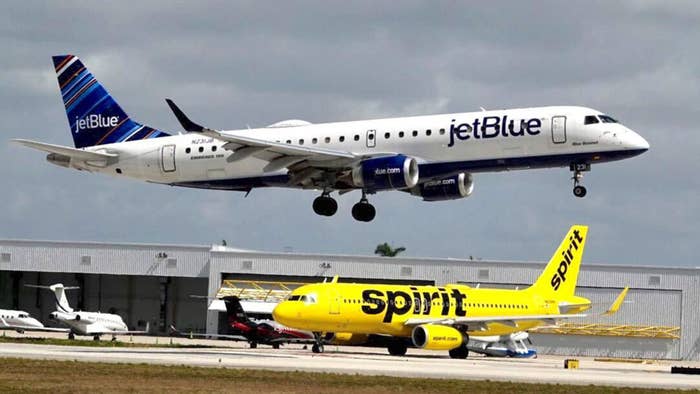 JetBlue airliner flies over Spirit Airlines jet.