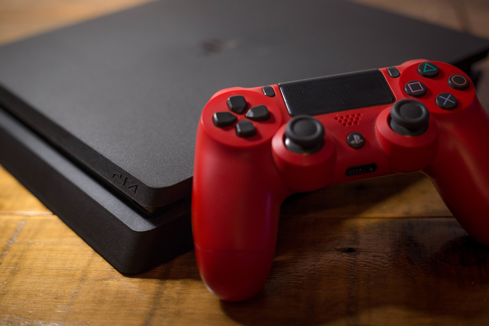 A Sony PlayStation 4 video game console with a red wireless controller