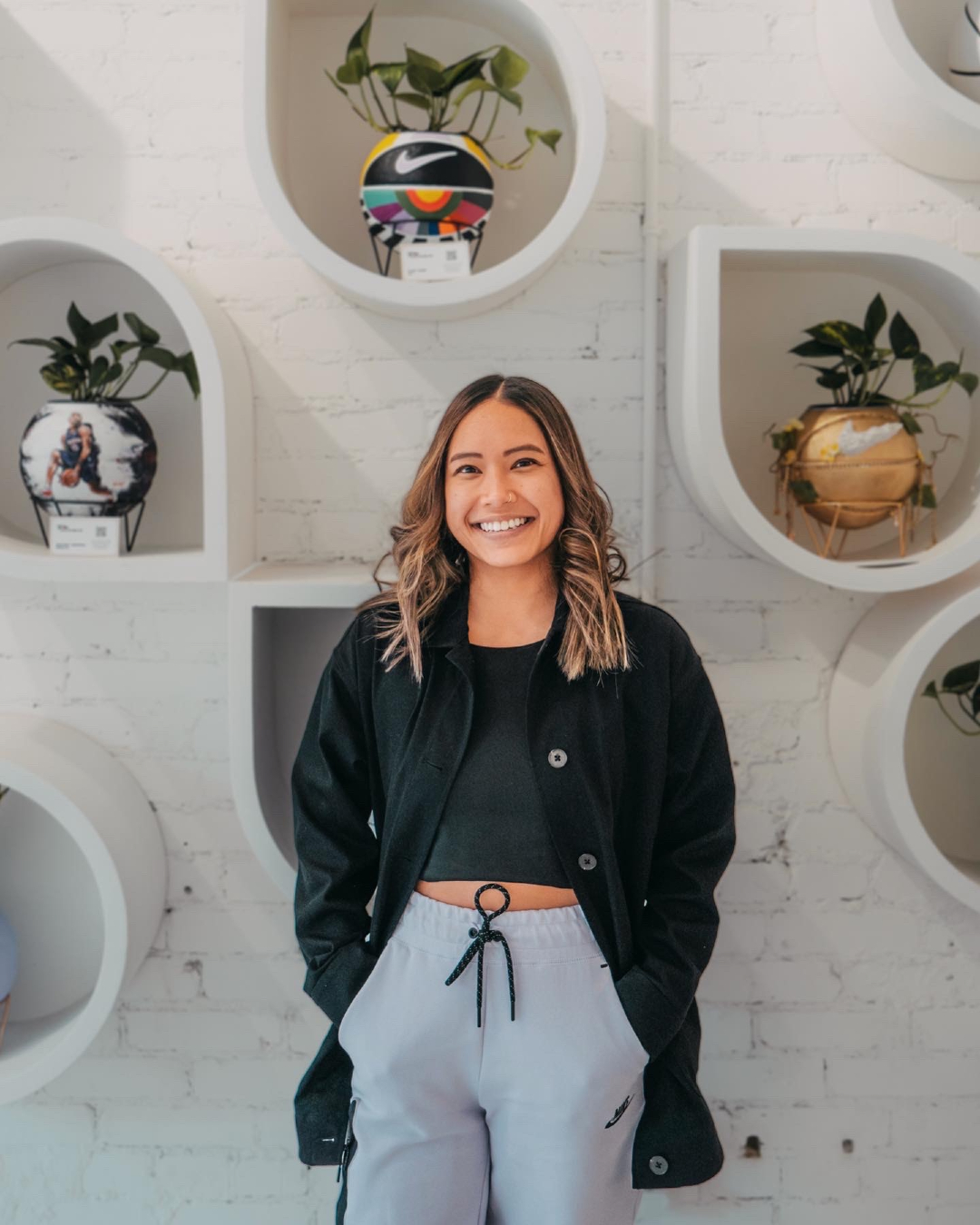 Olivia Ho, founder of The Give and Grow, standing in front of some of her work