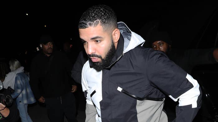 Drake walks into the night as paparazzi descends upon him.