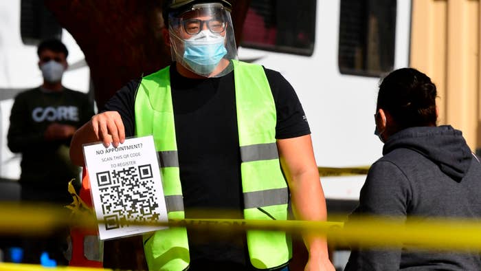 A testing center worker displays a copy of QR code for cellphone scanning of appointments.