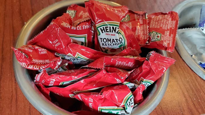 Close-up of container of Heinz brand ketchup packets in restaurant setting.
