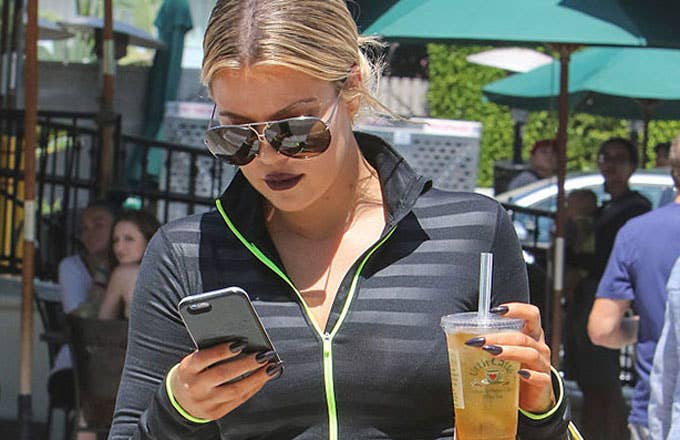 Khloe Kardashian looks at her phone.